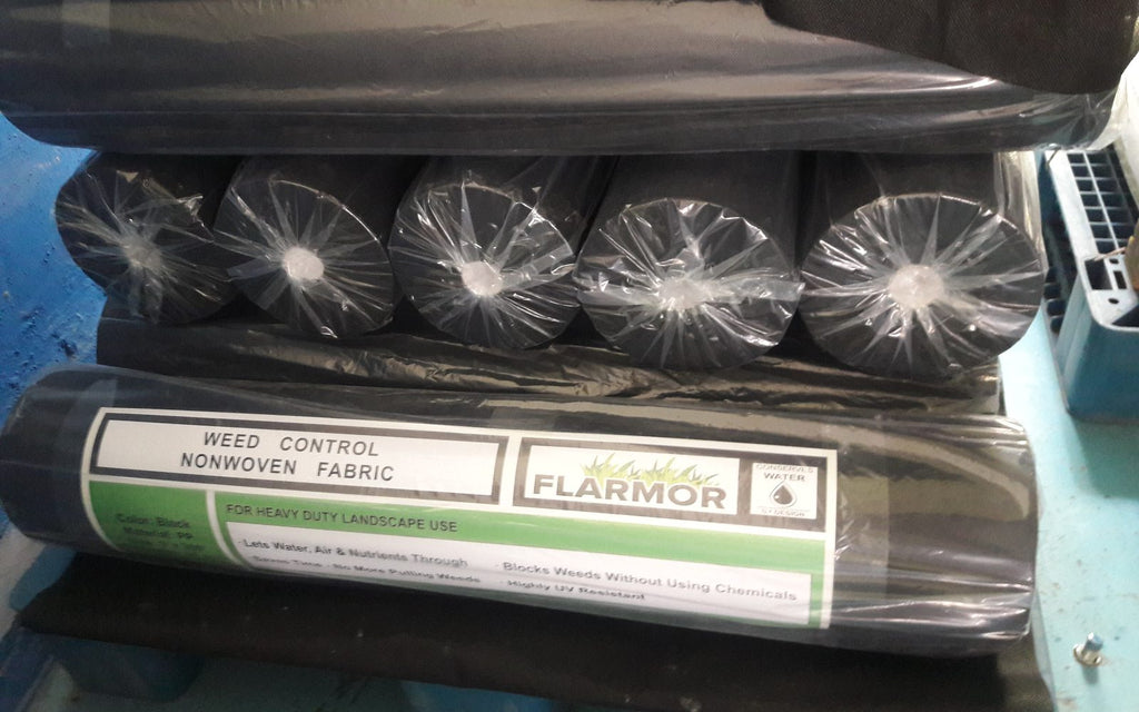 FLARMOR non-woven landscape fabric rolls stacked on a pallet, each with a FLARMOR weed control label, before shipment